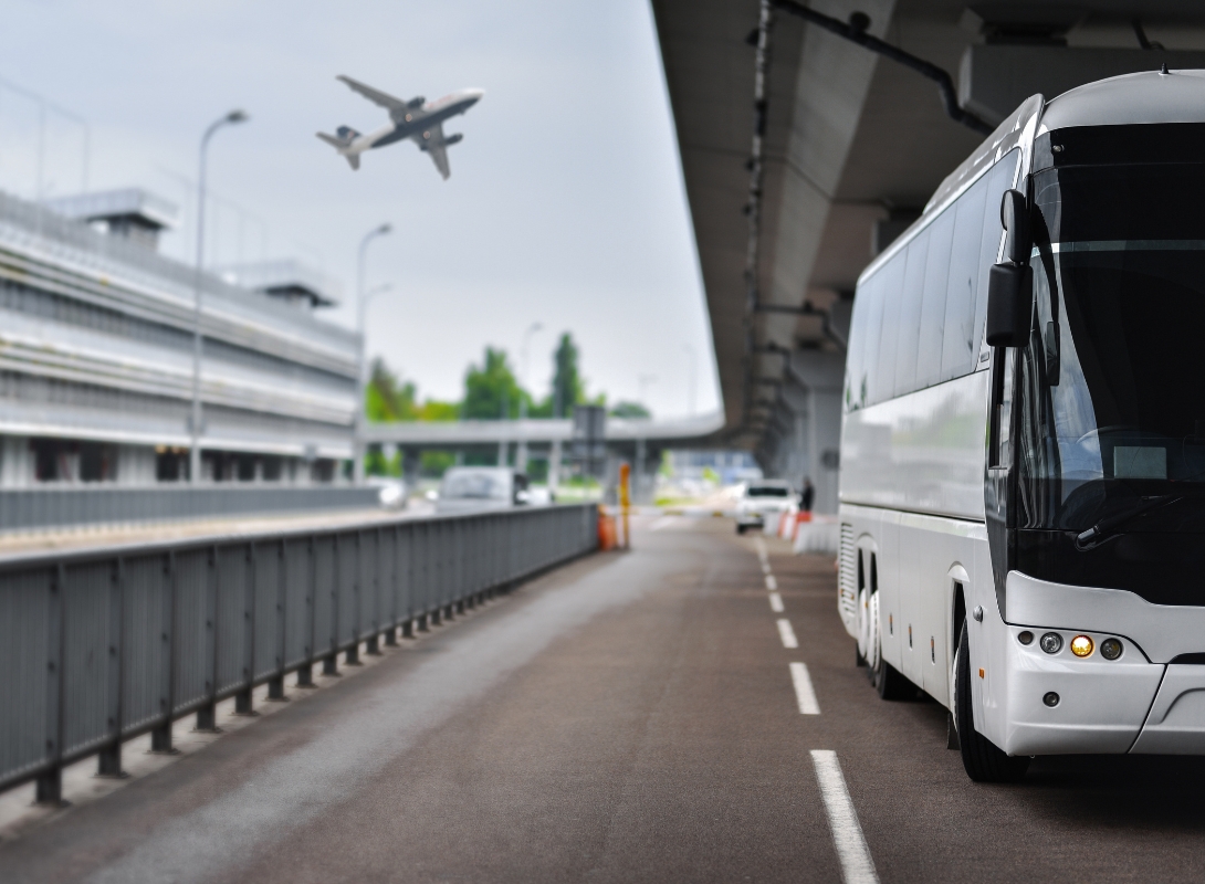 Un bus avec chauffeur arrive aux alentours d'un aéroport pour déposer les passagers.